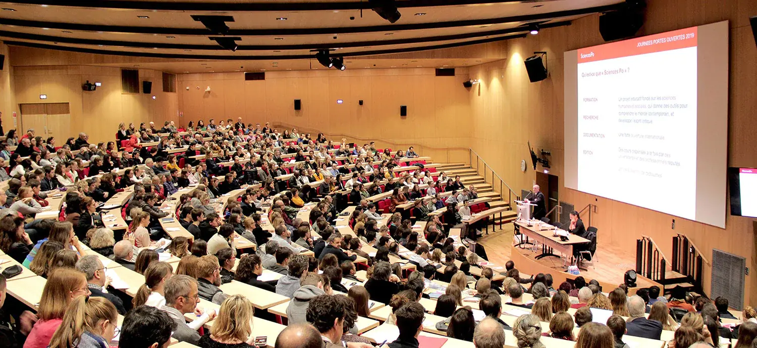 圆形剧场，数百名学生在此聆听讲台上两位教授的演讲。