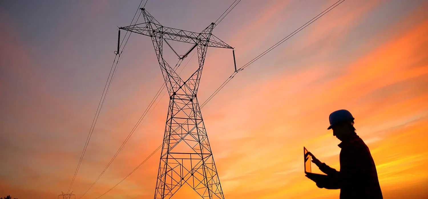 田野中的电塔,一名头戴建筑安全帽的男子正在电脑上检查各种元素。