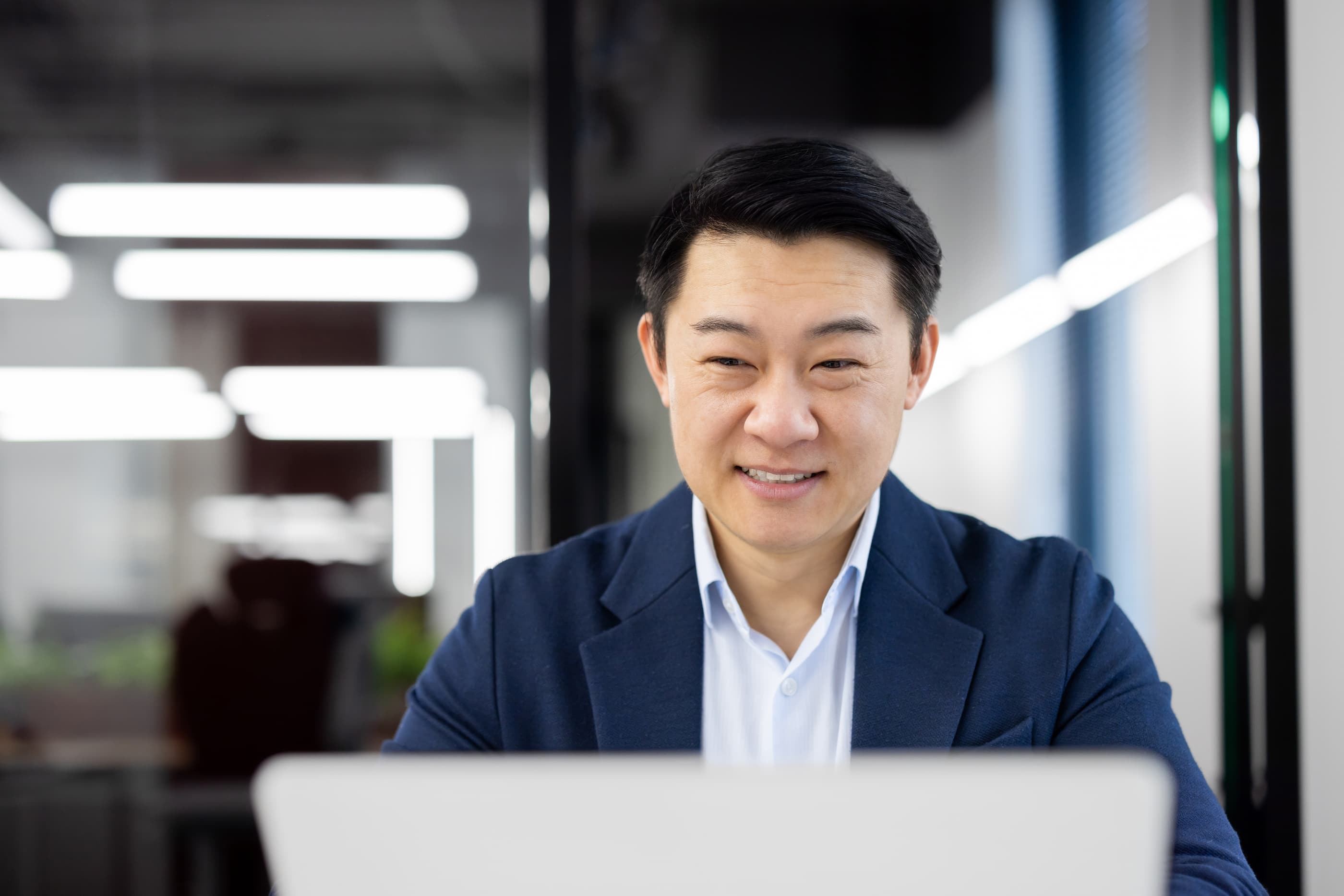 一位戴眼镜的微笑男子正在电脑前传输数据,以便从媒体过渡到 Ephoto Dam 数字资产管理软件。