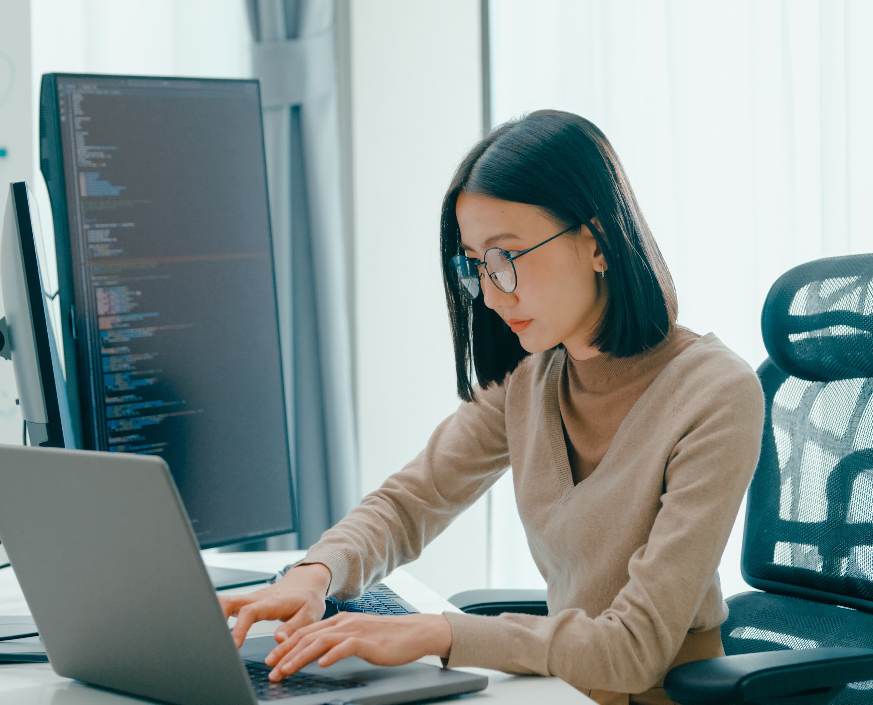 微笑着在电脑上工作的妇女，说明为学习 Ephoto Dam 照片库管理软件的功能而提供的支持。