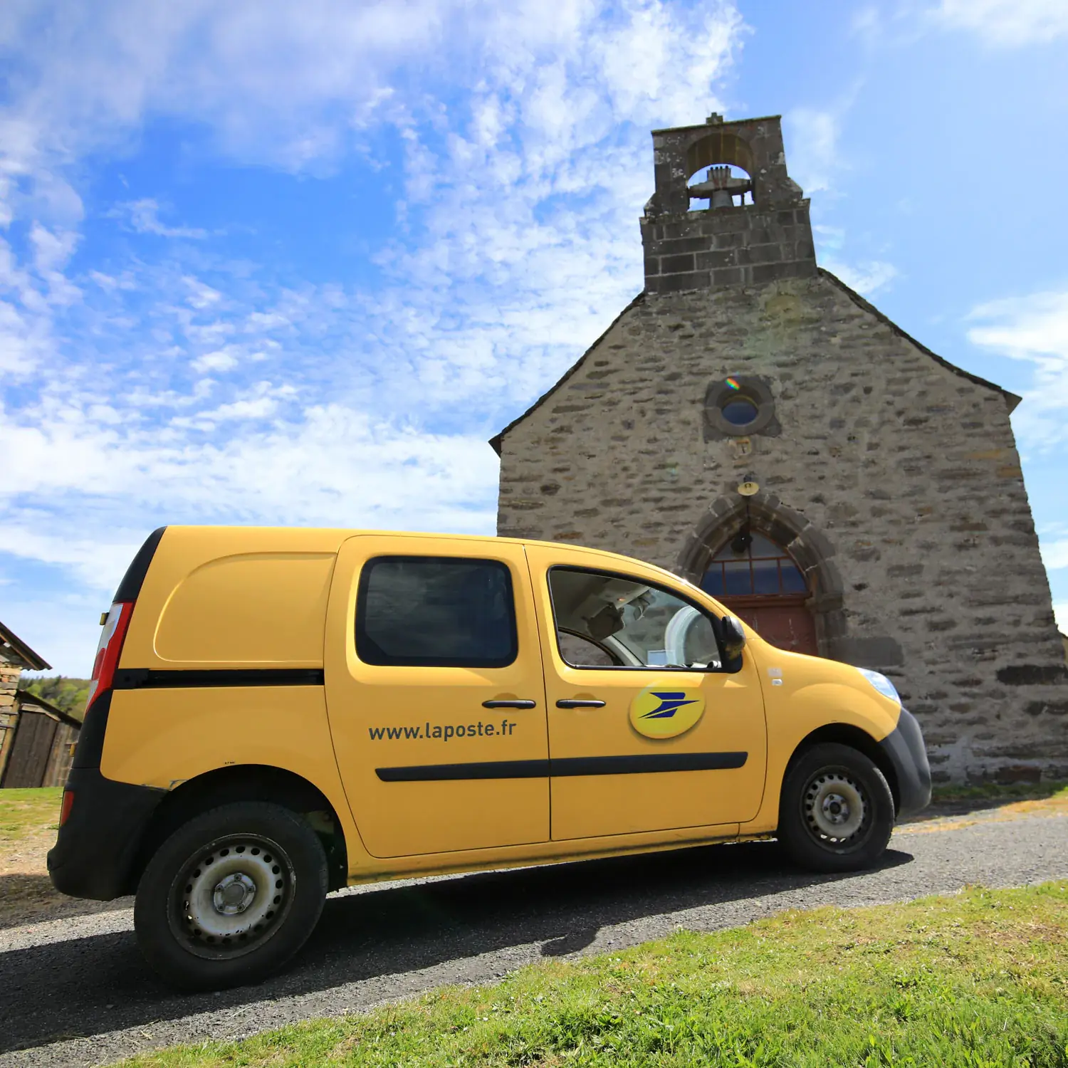 印有 La Poste 徽标的黄色汽车停在小教堂前。