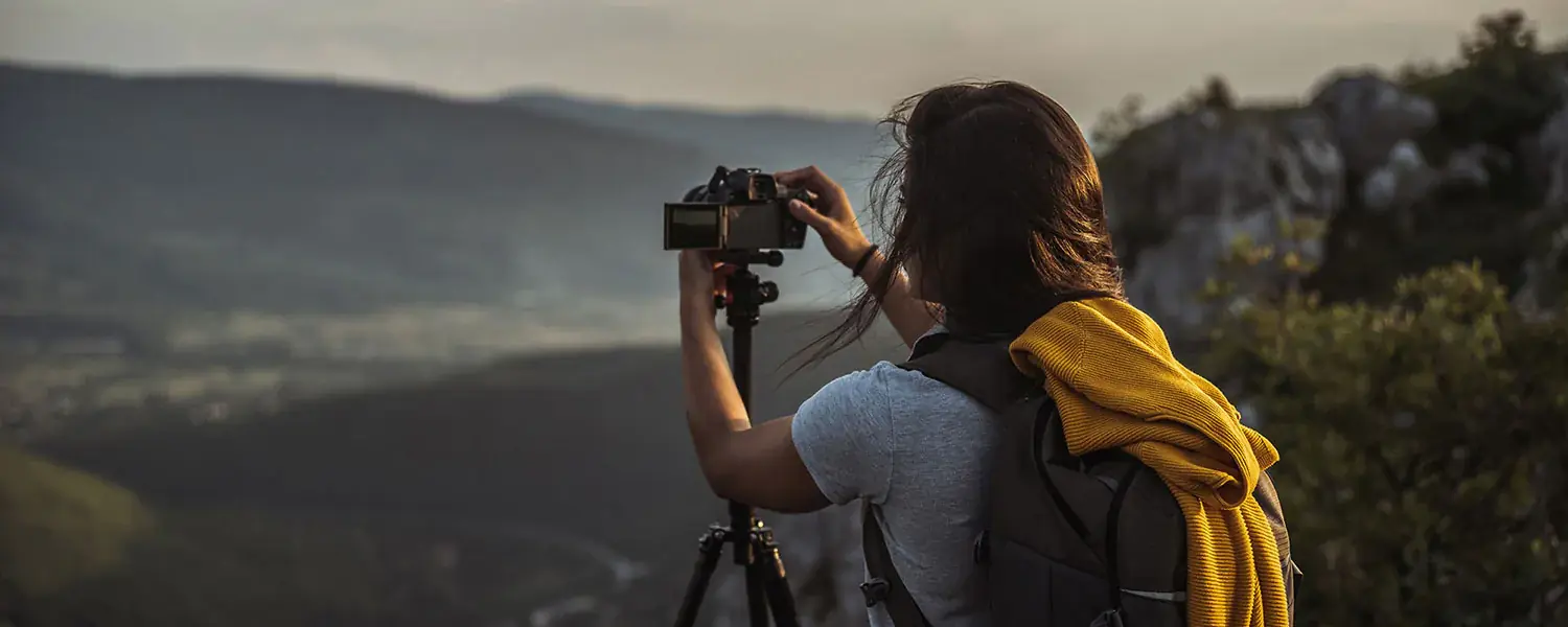 女子手持相机在三脚架上拍摄全景。